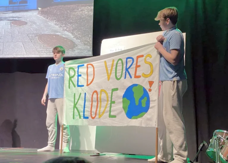 Engagerede elever på scenen med plakat "Red vores klode"